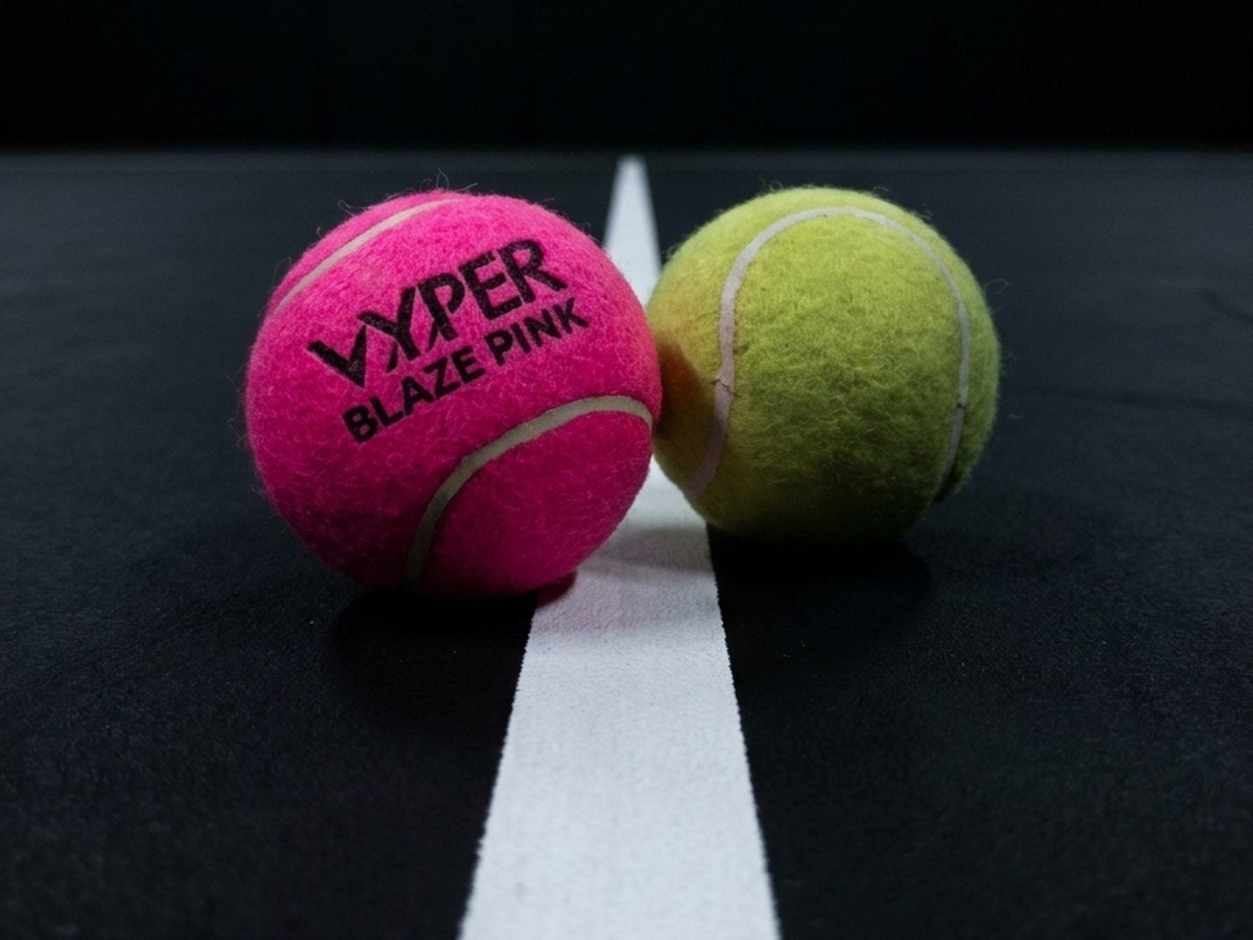 VYPER Blaze Pink neben einem gelben Padel-Ball auf dunklem Court bei Hallenlicht